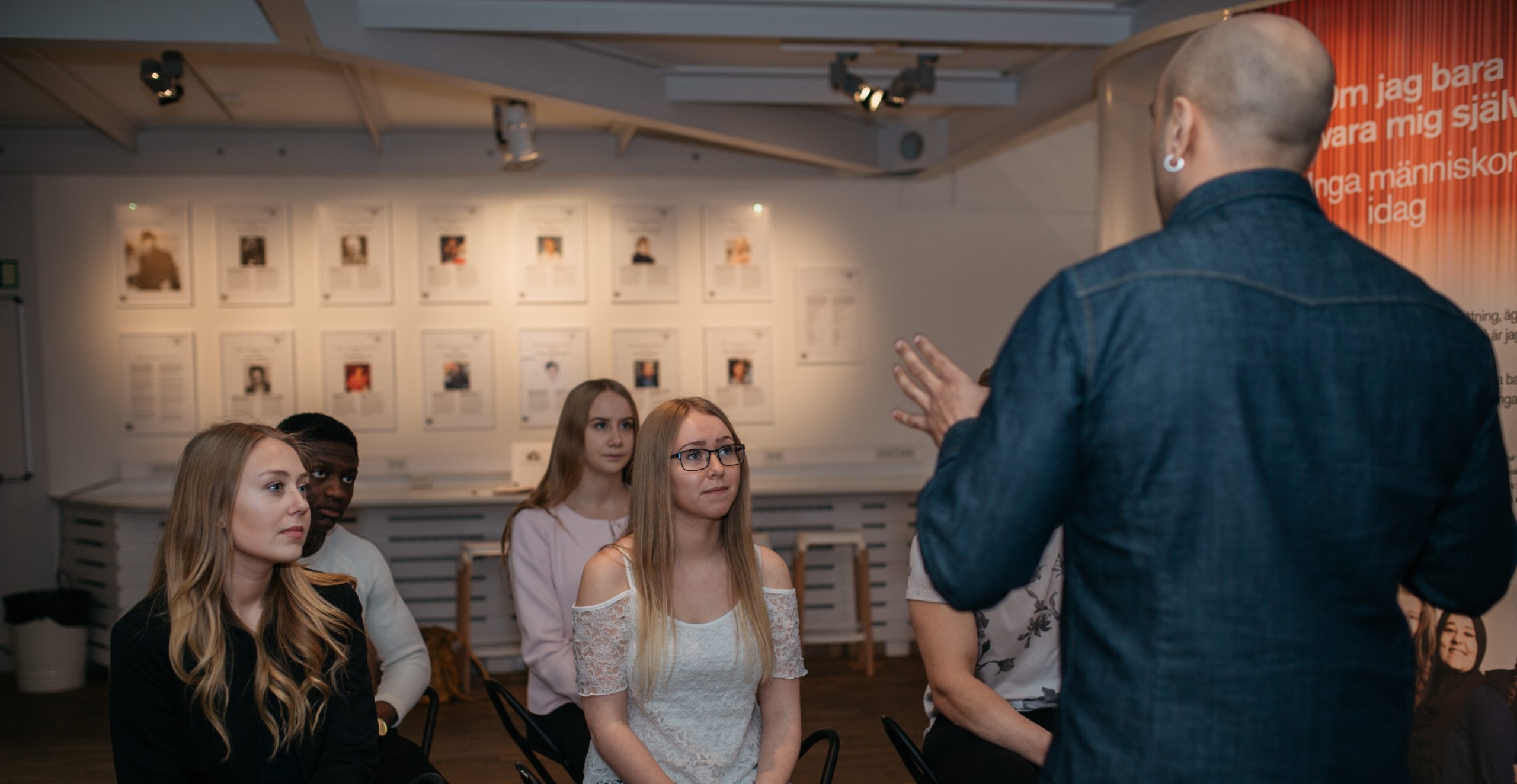 En grupp elever lyssnar på en pedagog i Forum för levande historias utställningslokal.